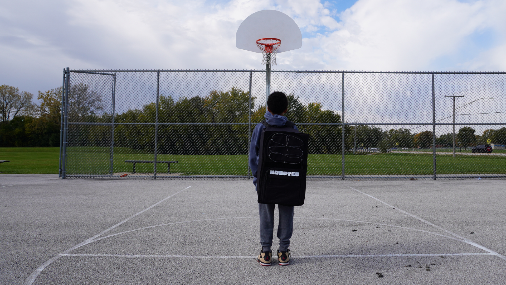 Young Hooper wearing HOOPTEQ looking at goal on outdoor court