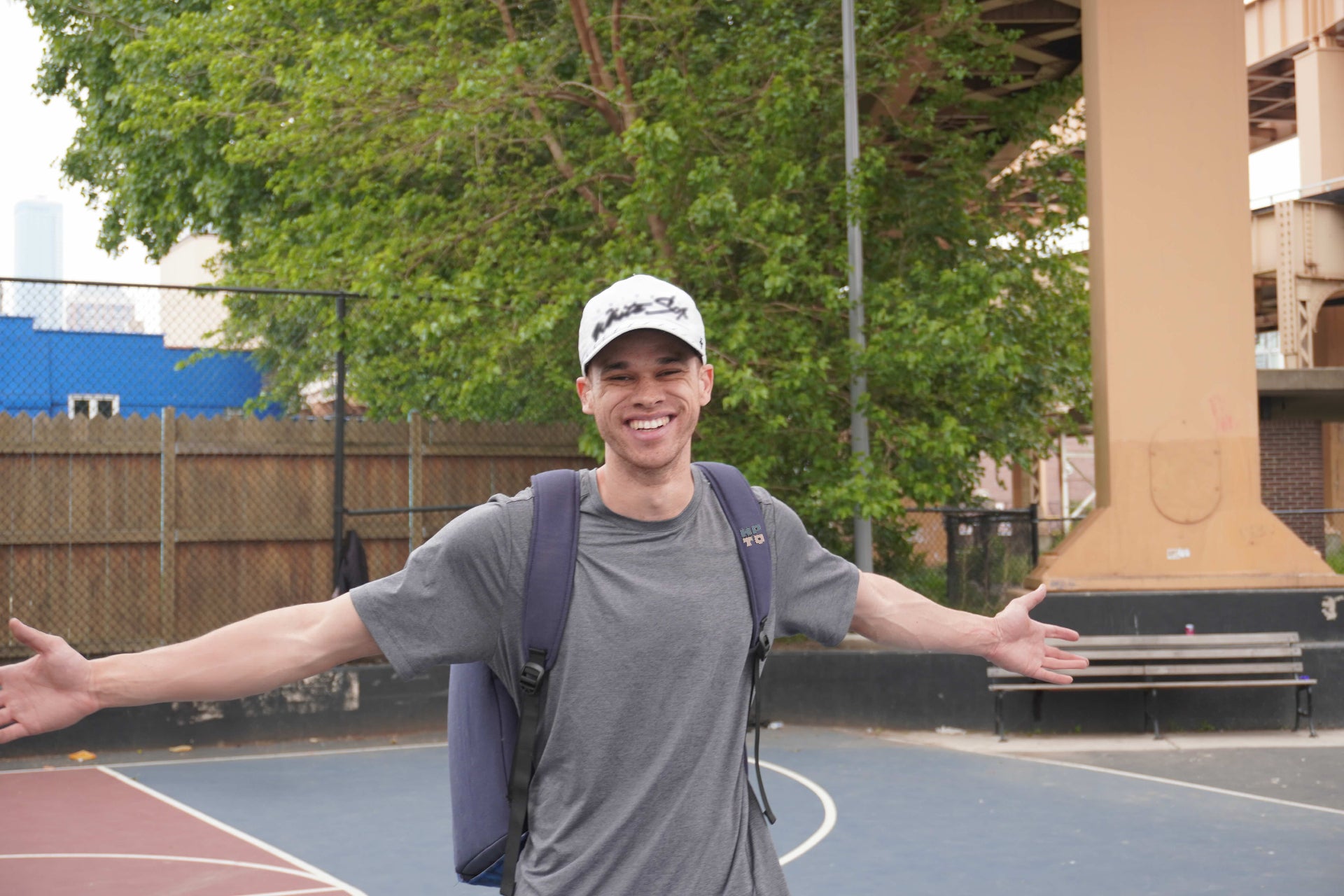 Eric Roberson, founder of HOOPTEQ, smiling while wearing the backpack on a basketball court.