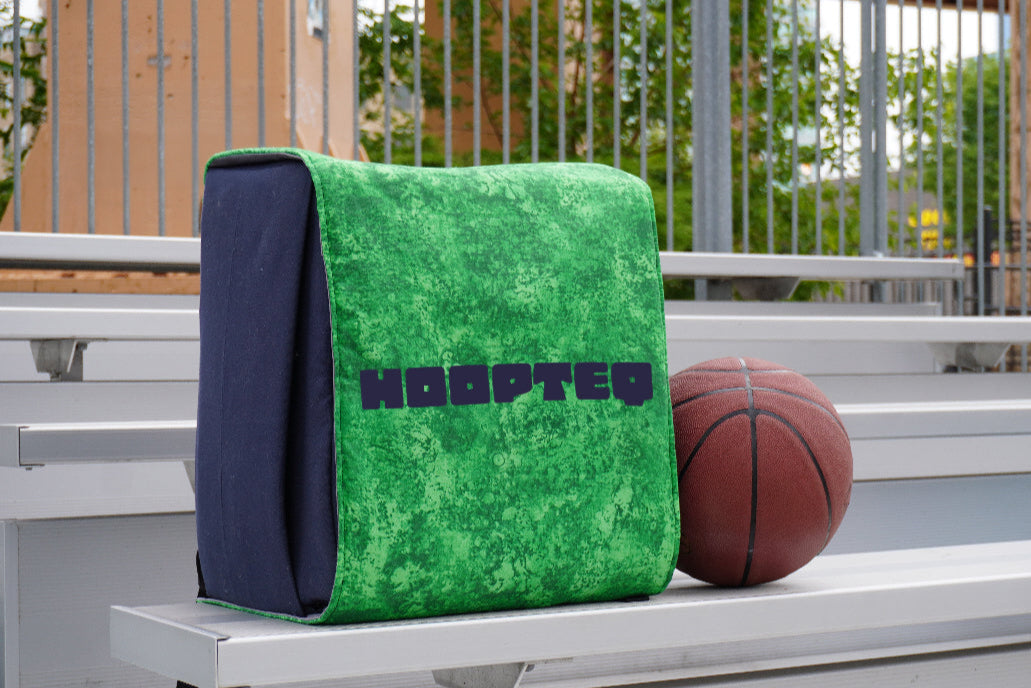 Green HOOPTEQ backpack with colored skin next to basketball on court