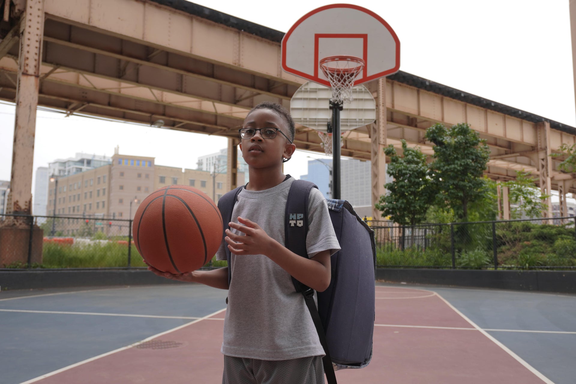 Young boy holding a basketball while wearing the HOOPTEQ backpack portable shooting machine