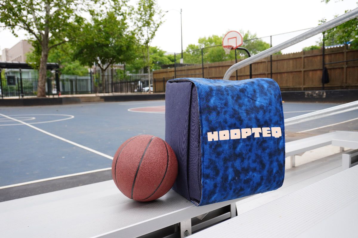 Navy HOOPTEQ backpack with colored skin next to basketball on court