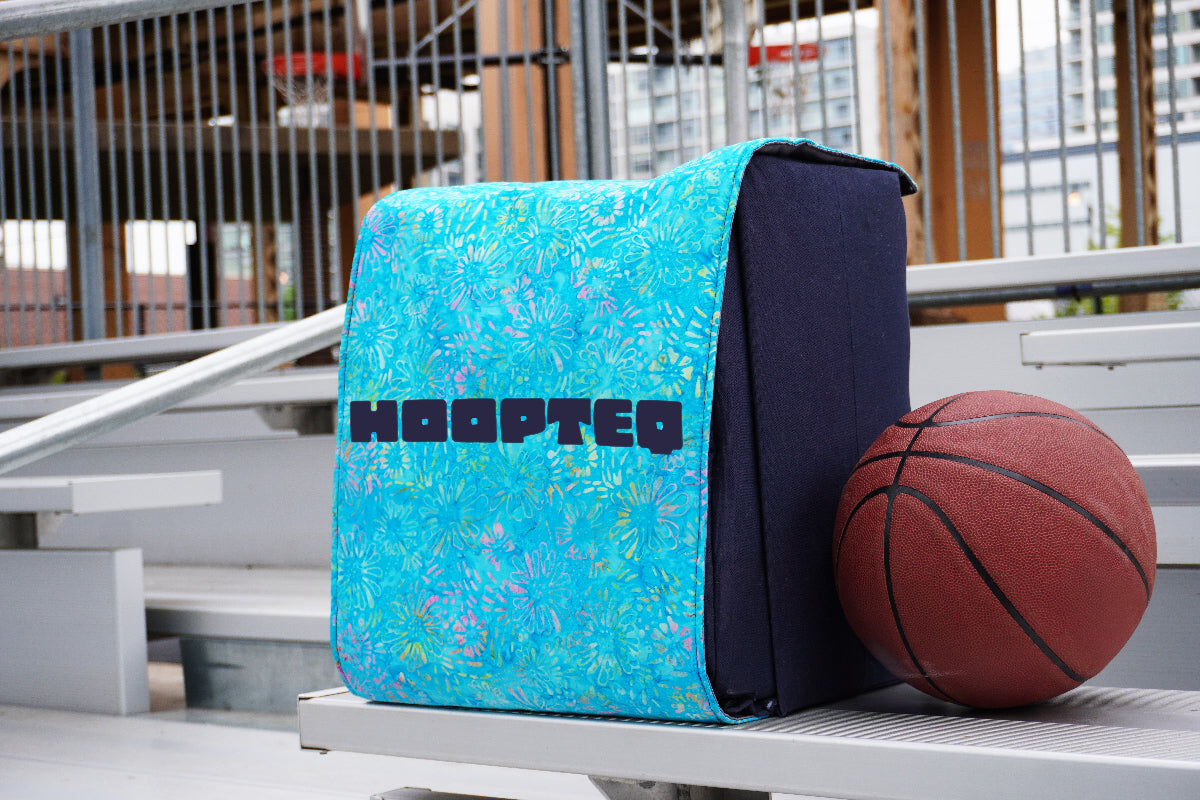 Sky blue HOOPTEQ backpack with colored skin next to basketball on court